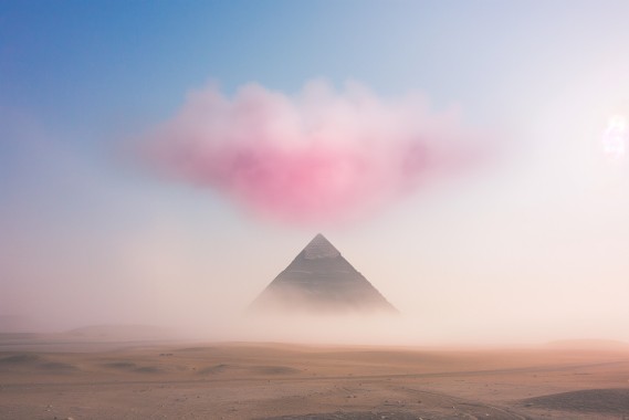 photo of a single pink cloud looking like cotton ball floating high above a misty sand desert with a black golden shining pyramid in the background, bluish misty dust --ar 3:2 --style raw --stylize 50